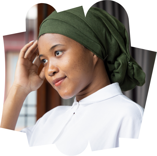 A young woman wearing a smart white shirt gently touching her head smiling