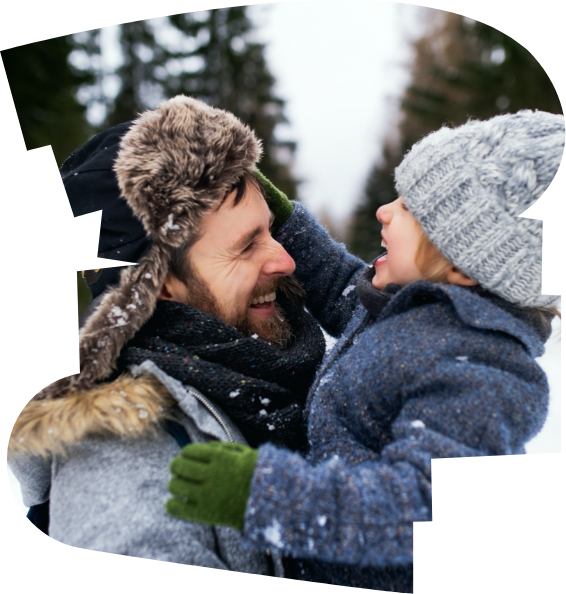 A man and child wrapped up warm playing in the snow